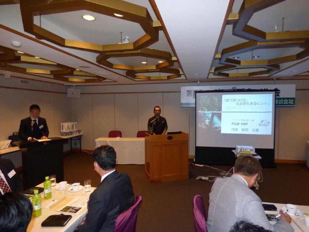 講演会場でマイクの前に立ち、スライドを映しながら自然について語る服部太喜