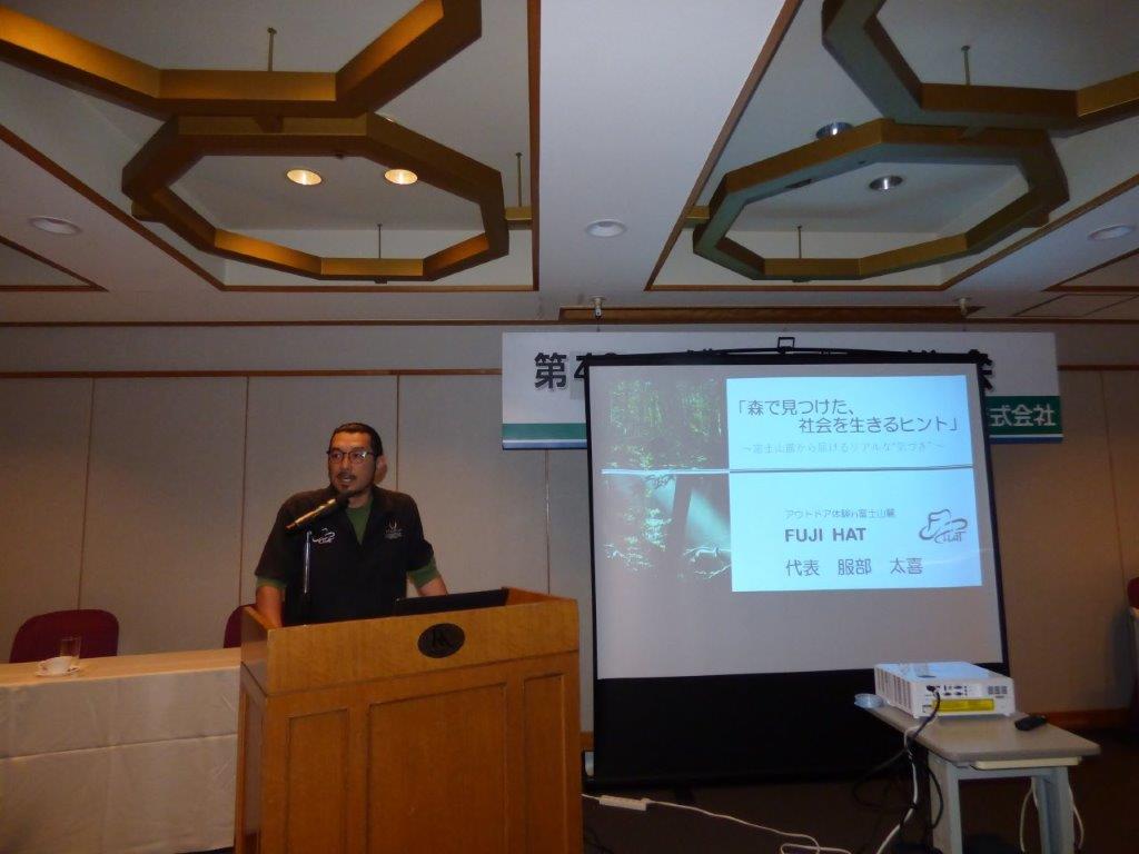 「森で見つけた、社会を生きるヒント」のスライドを背に、講演を進める服部太喜の様子