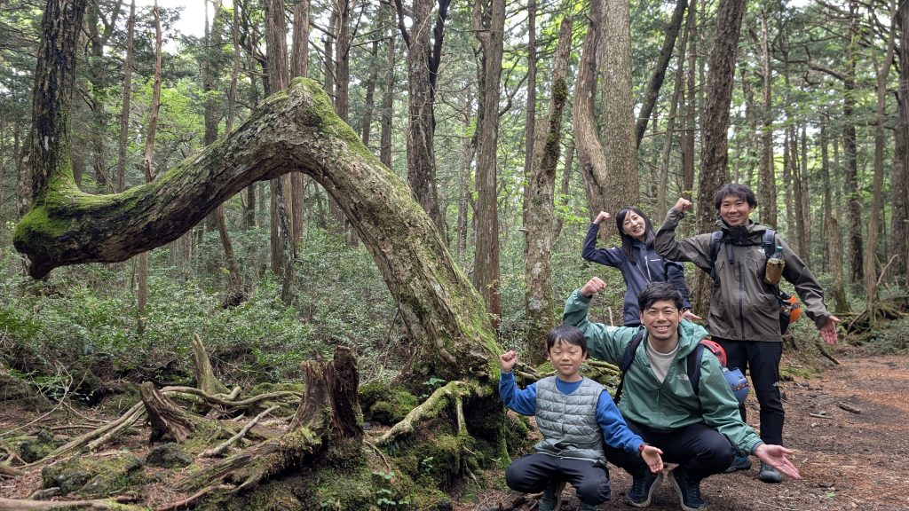 樹海の中でポーズをとるツアー参加者たちの集合写真
